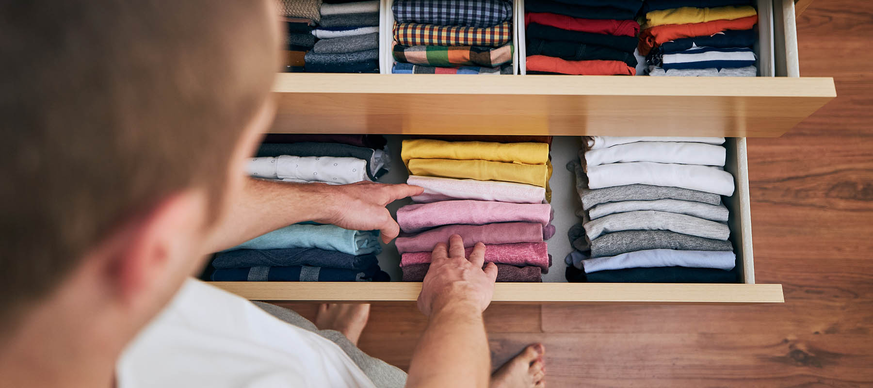 man organizing shirts in drawer